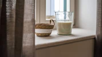 A glass of milk on a windowsill next to a woven basket.