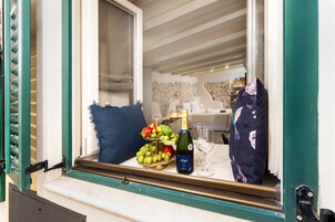 Una ventana con una mesa dispuesta, una botella de champán, copas y una bandeja de frutas.