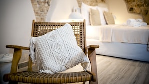 A cozy room with a wicker chair, a white knitted throw, a bed with white linens, and a stone wall. - Yellow House Rovinj (Rovinj)