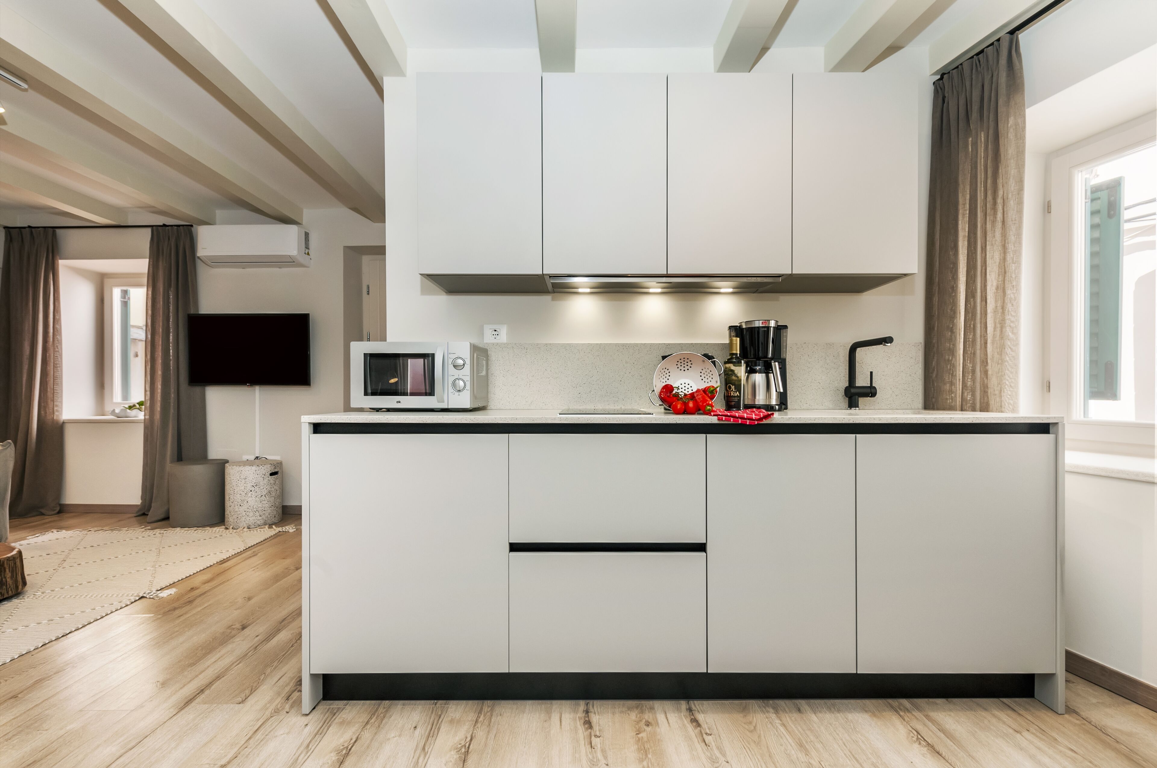 Cozinha moderna com armários brancos, micro-ondas e máquina de café.