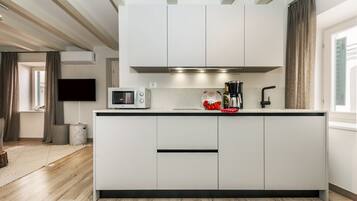 Cozinha moderna com armários brancos, micro-ondas e máquina de café.