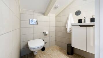A small, modern bathroom with a toilet, sink, and a towel hanging on the wall.