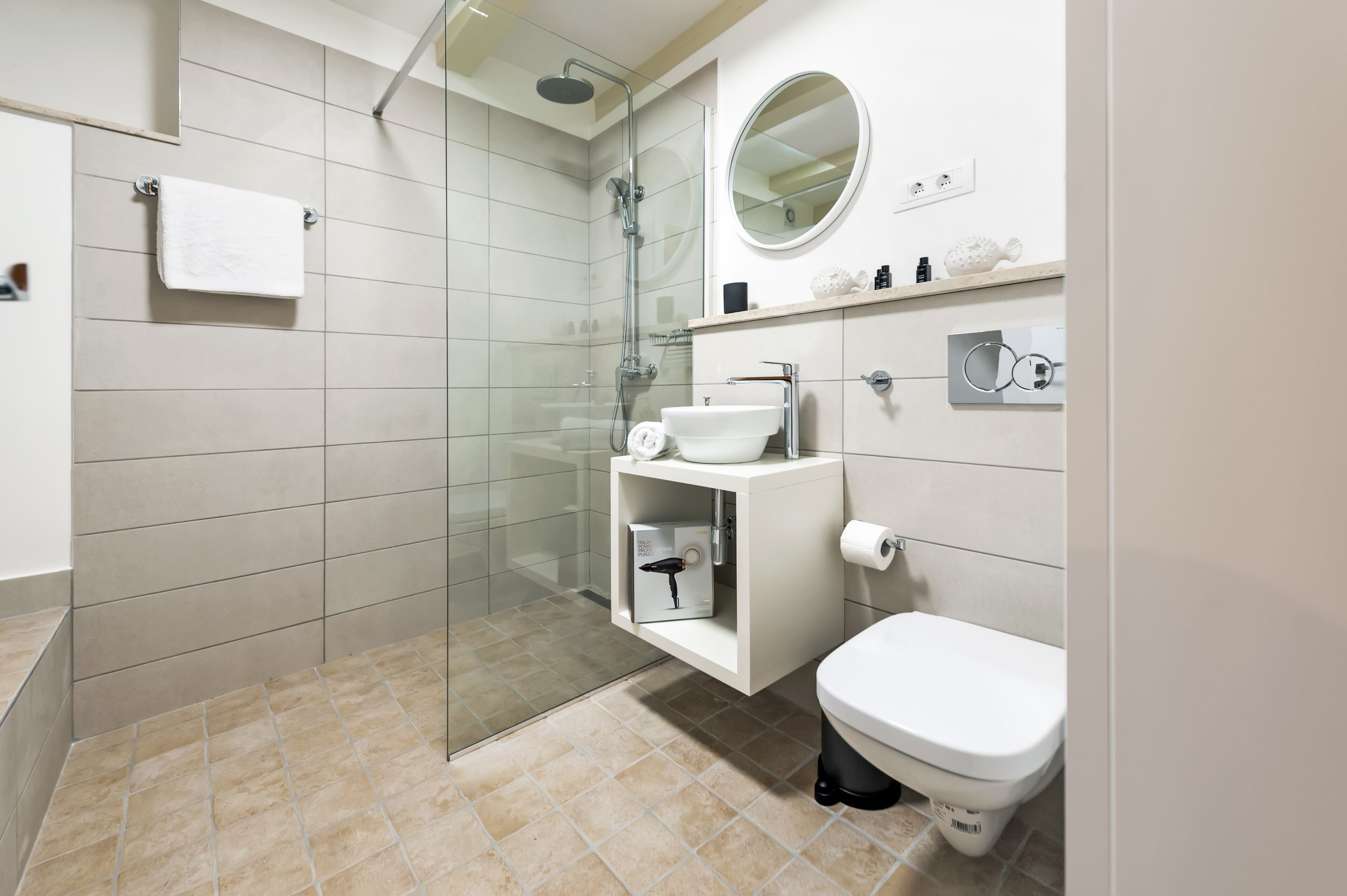 A modern bathroom with a glass-enclosed shower, a white sink, and a toilet.