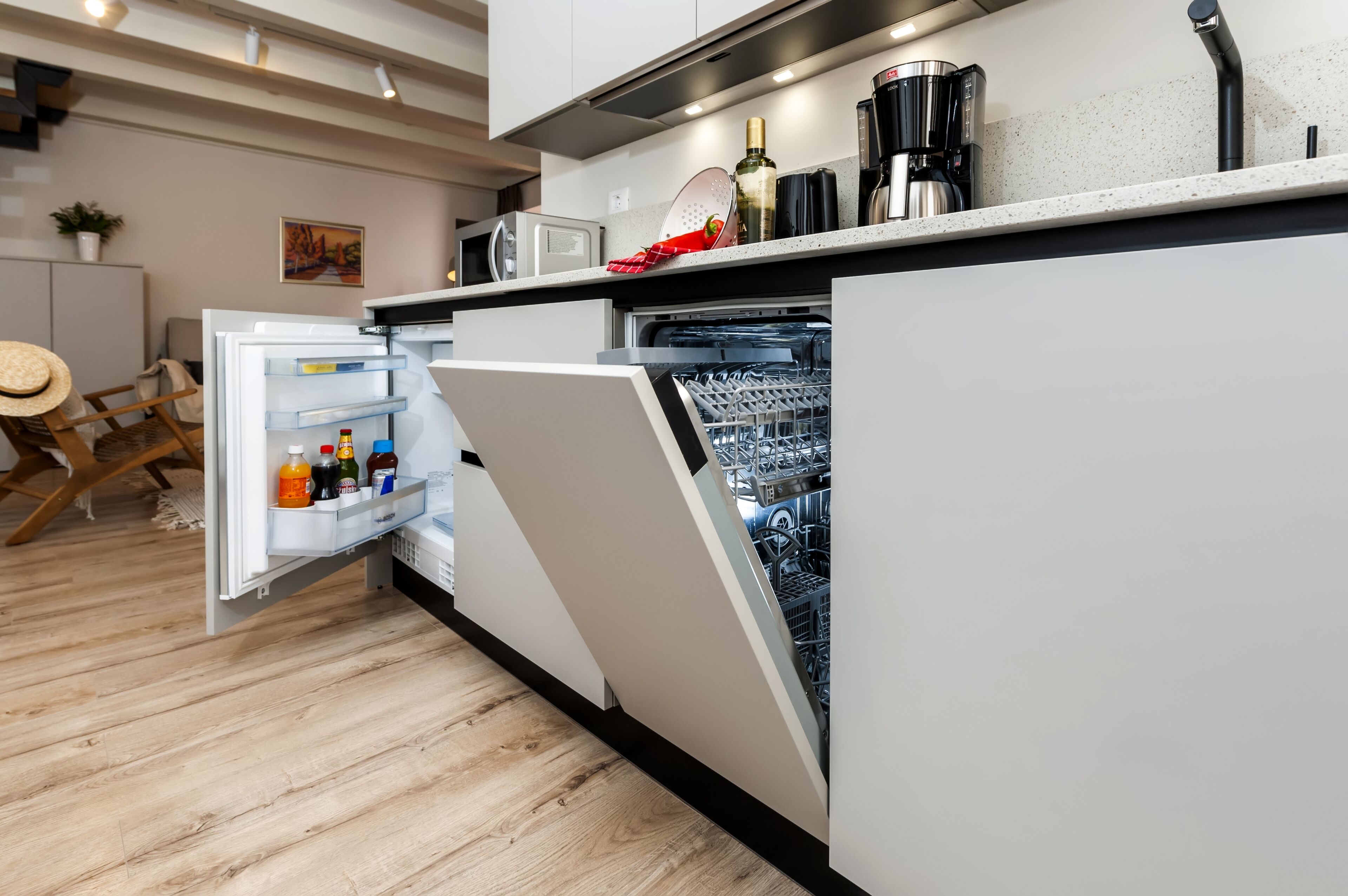 A modern kitchen with a built-in dishwasher, a microwave, and a coffee maker.