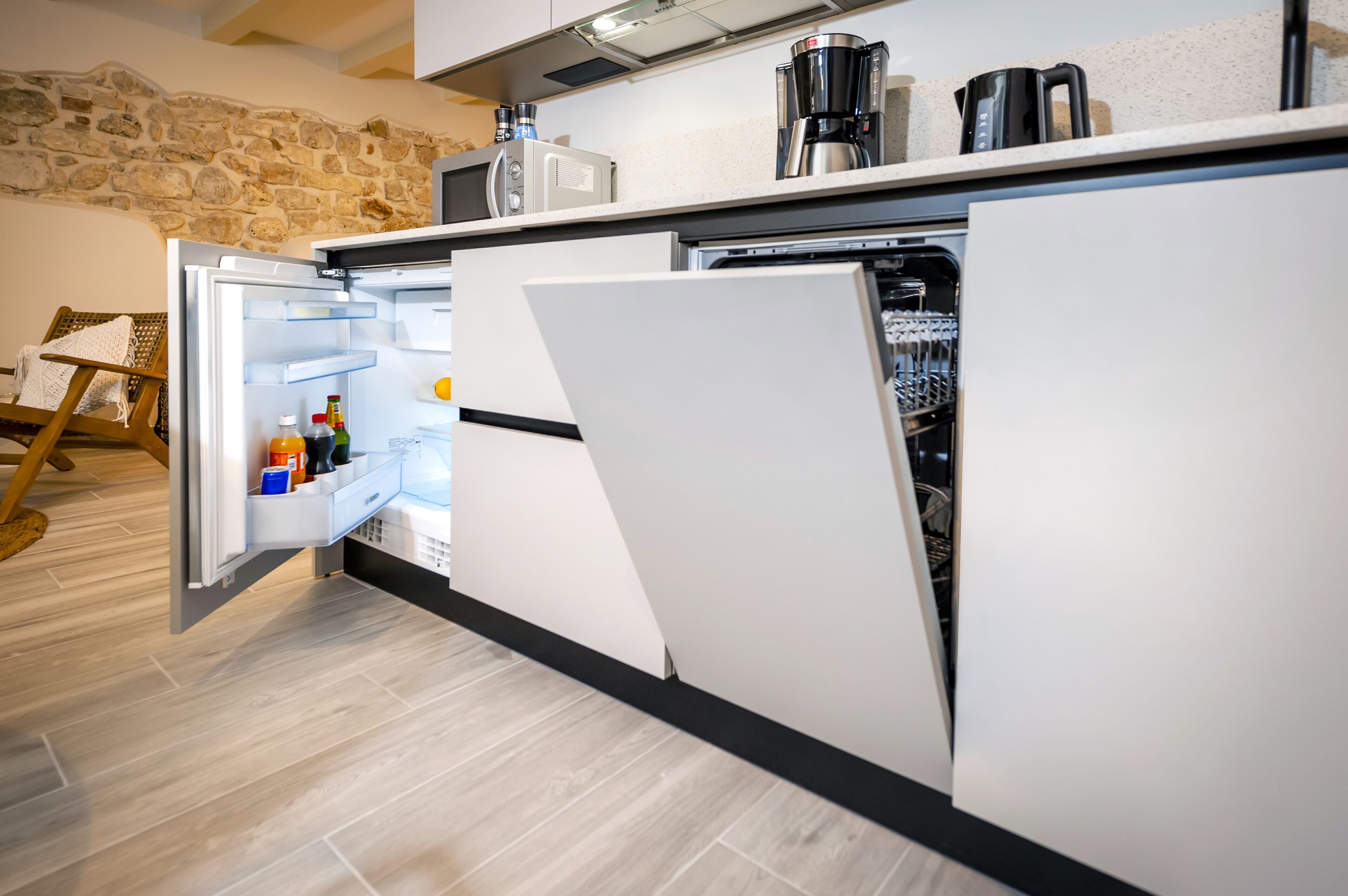 A modern kitchen with a built-in refrigerator, a coffee maker, and a kettle on the countertop.