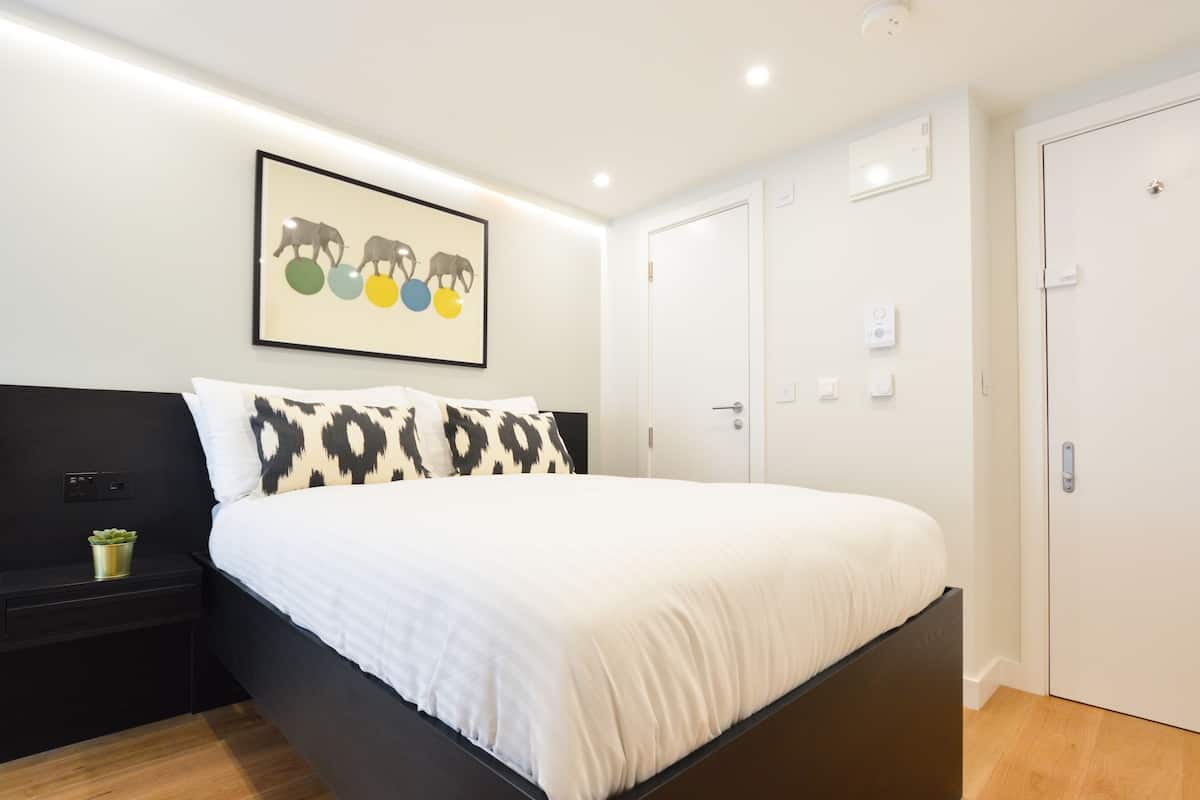 Ein Schlafzimmer mit einem Bett, einem Nachttisch, einem Wandbild und einer Tür.