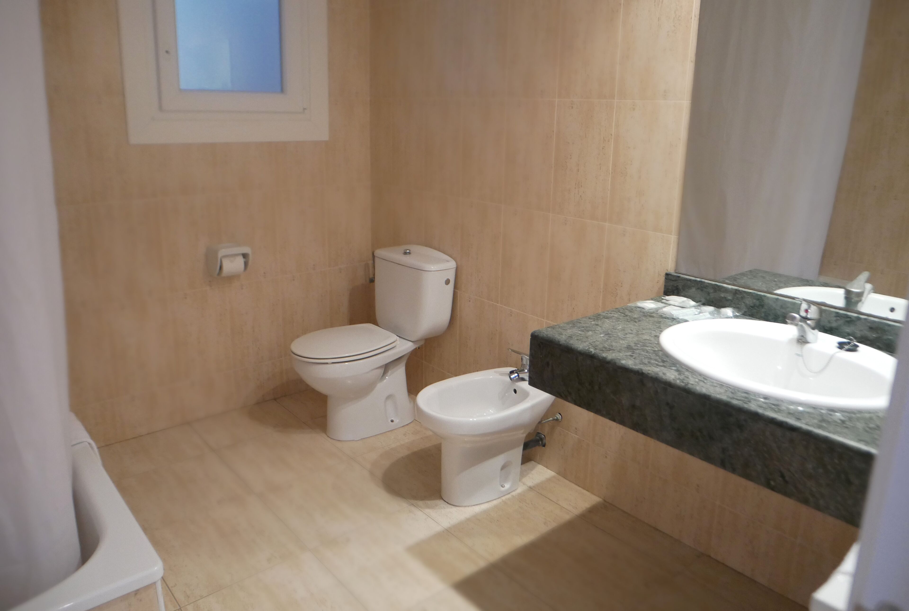 Un baño con inodoro, bidé y lavabo.
