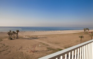 A beach with palm trees, a lifeguard tower, and a clear view of the ocean. - Hotel Brisamar Suites (El Vendrell)
