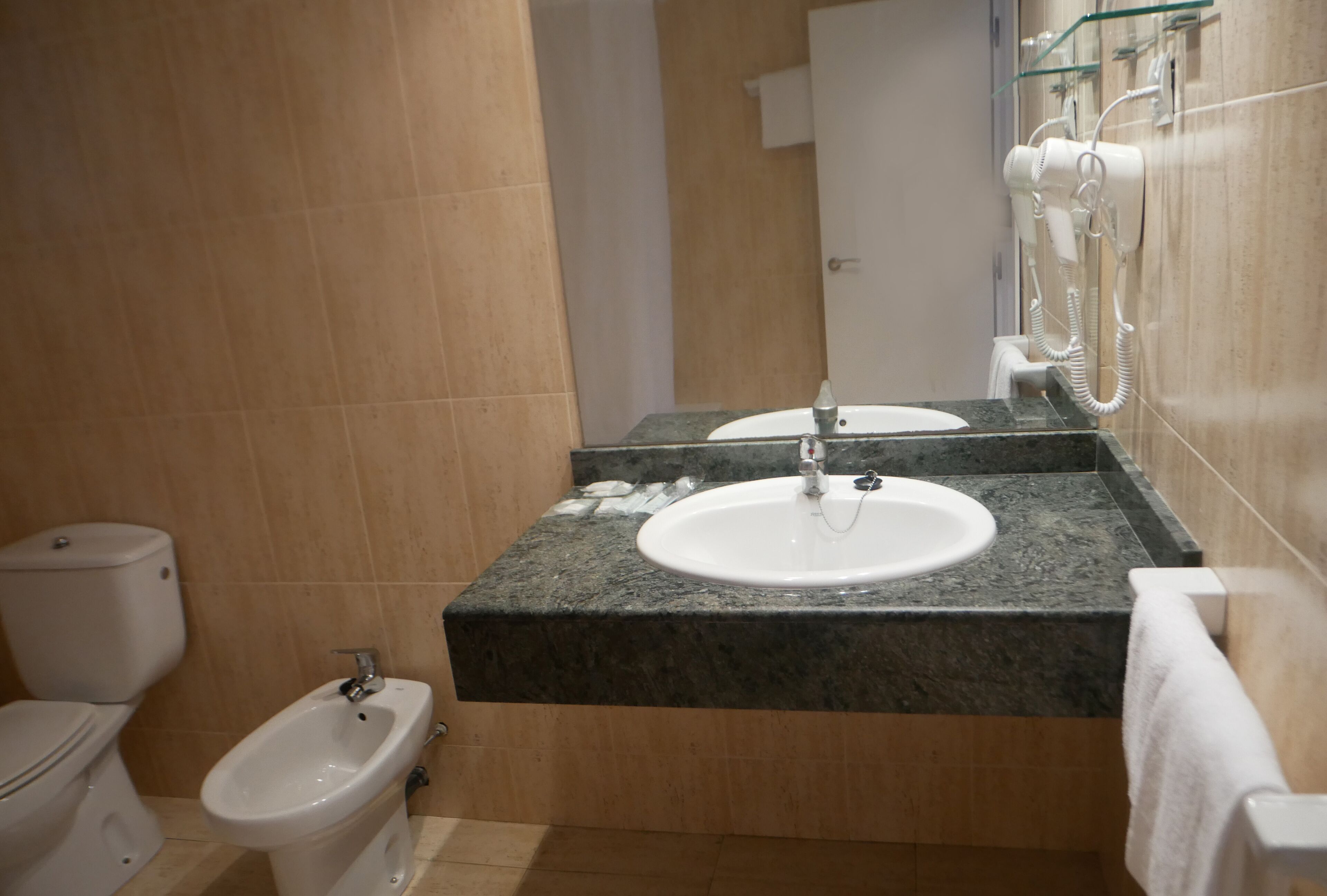 Ein Badezimmer mit Toilette, Bidet, Waschbecken und Spiegel.