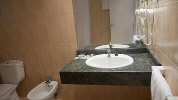 Ein Badezimmer mit Toilette, Bidet, Waschbecken und Spiegel.