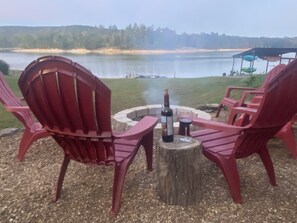 Un espacio para sentarse junto al lago, con sillas Adirondack y un brasero.