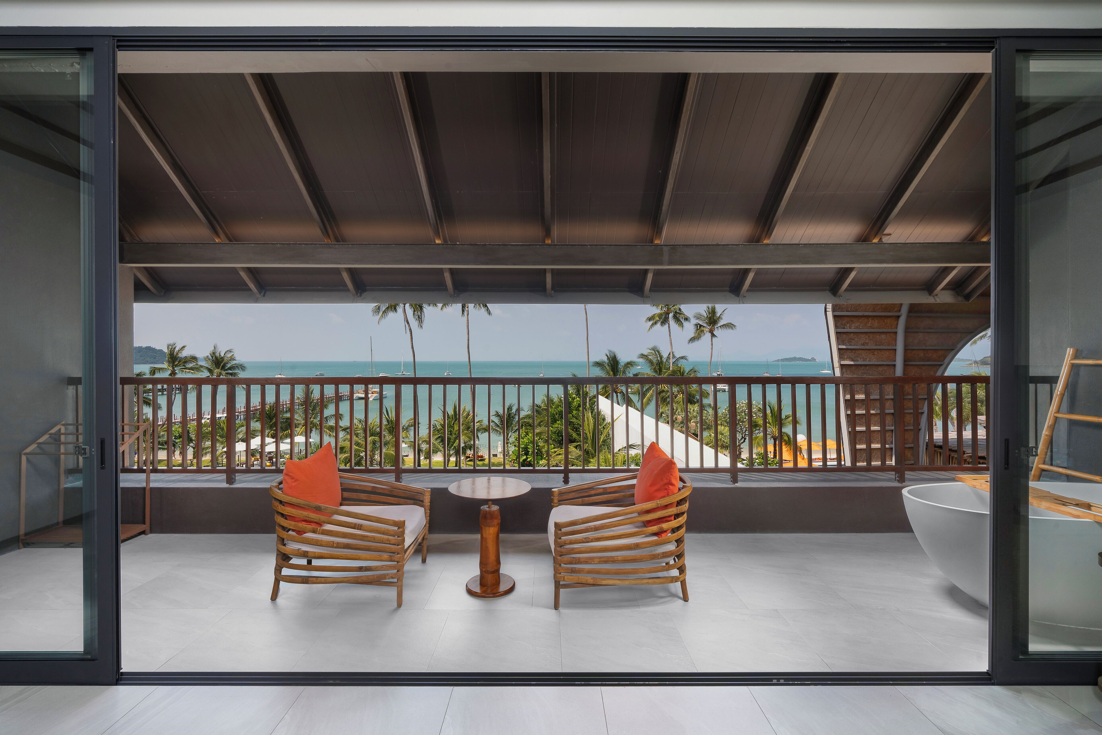 A balcony with two wooden chairs, a round table, and a large white bowl.
