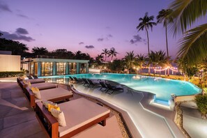 A swimming pool with lounge chairs and a bar area.