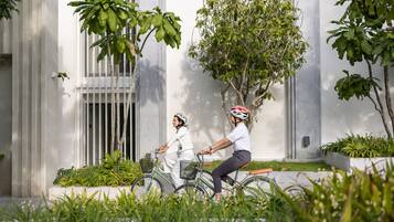Twee personen fietsen in een binnenplaats met een modern gebouw op de achtergrond.