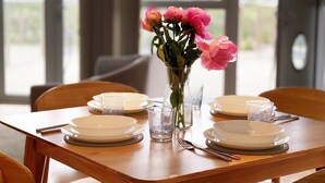 Una mesa de comedor preparada con platos, vasos y un florero con flores.