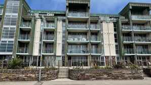 Un edificio residencial de varios pisos con balcones, fachada de piedra y cielo despejado.