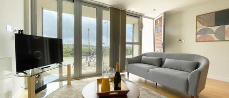 Relax in this stylish living room with a flat-screen TV, comfortable sofa, and a coffee table, plus access to a balcony with countryside views.