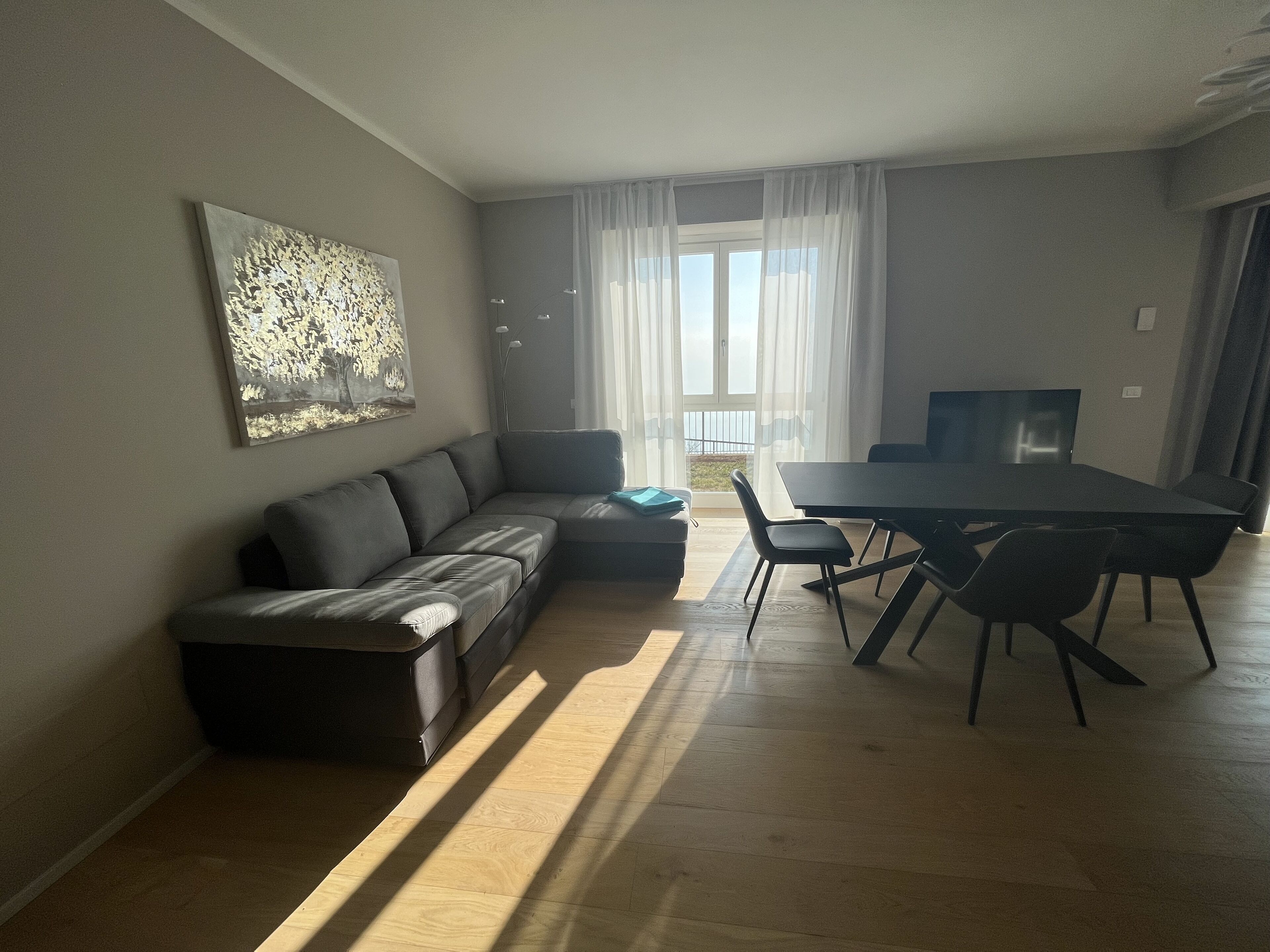 Ein modernes Wohnzimmer mit einer Eckcouch, einem Esstisch mit Stühlen und einem Flachbildfernseher.