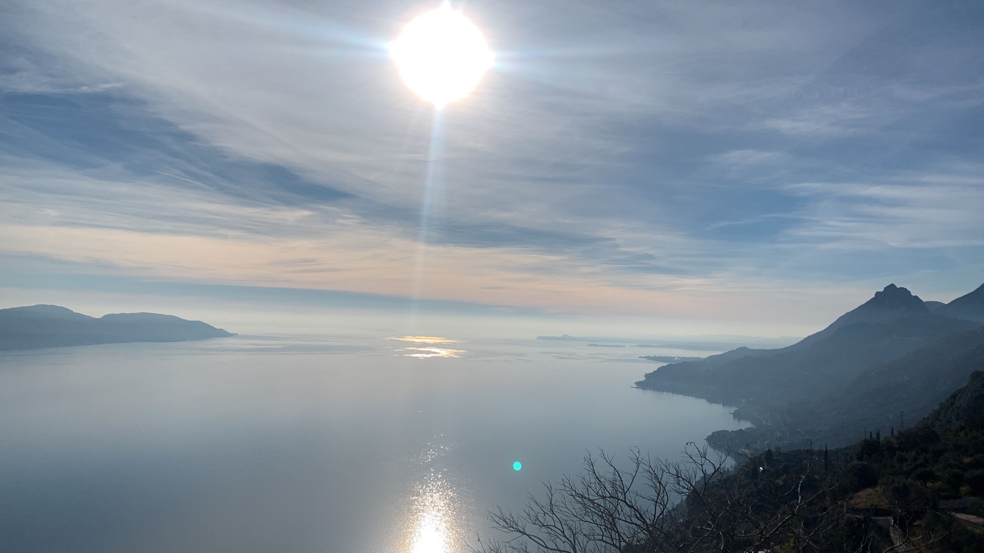 A panoramic view of a calm lake with mountains in the background and a clear sky.