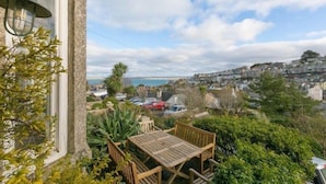Une terrasse avec une table et des chaises donnant sur une ville côtière.
