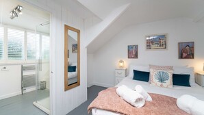 Une chambre dotée d’un grand lit, d’une douche à parois de verre et d’œuvres d’art accrochées aux murs.