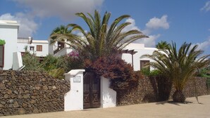Edifici blanc amb mur de pedra i una porta.