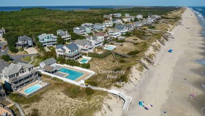 Vista aérea de una comunidad costera con casas, piscina comunitaria y playa.