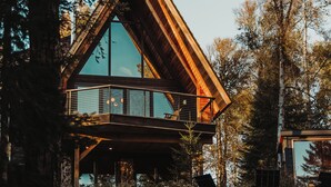 A modern cabin with a large glass balcony, surrounded by trees. - The Minne Stuga  (Grand Marais)