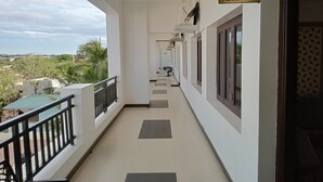 Zona de recepción de un hotel con balcón que da a una piscina y vegetación.