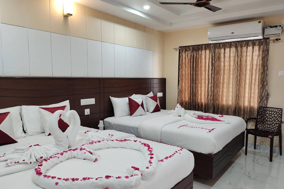 A hotel room with two beds, a ceiling fan, an air conditioning unit, and a chair.