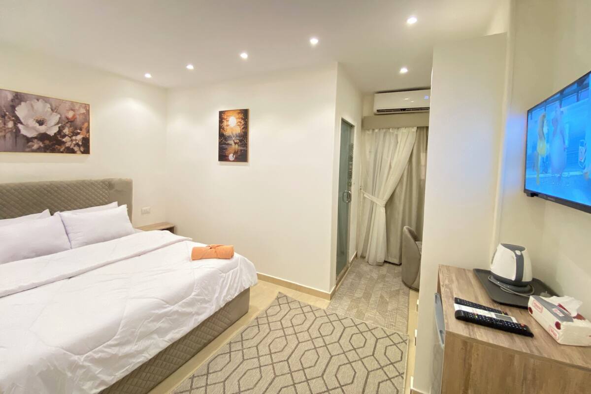 A hotel room with a bed, a TV, a remote control, and a coffee maker.
