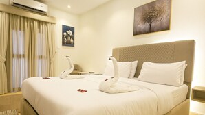 Una habitación de hotel con una cama grande, cabecera, mesita de noche y un cuadro en la pared.