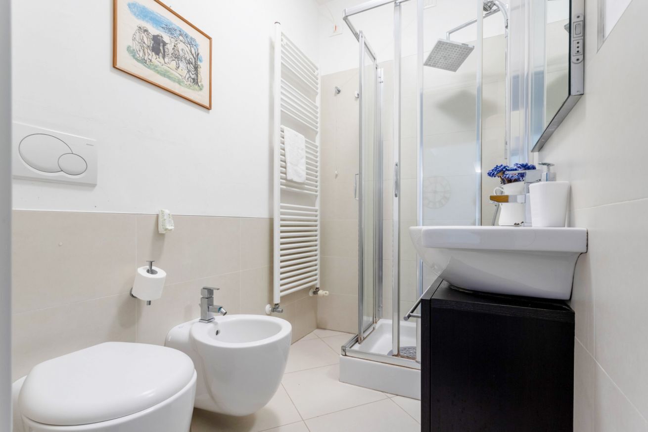Une salle de bain équipée de toilettes, d’un bidet, d’une douche et d’un lavabo.