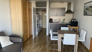 Un espacio habitable compacto con kitchenette, comedor y zona de estar.