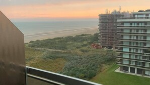 Un balcón con vistas a la costa, que incluye una playa y un edificio en construcción.