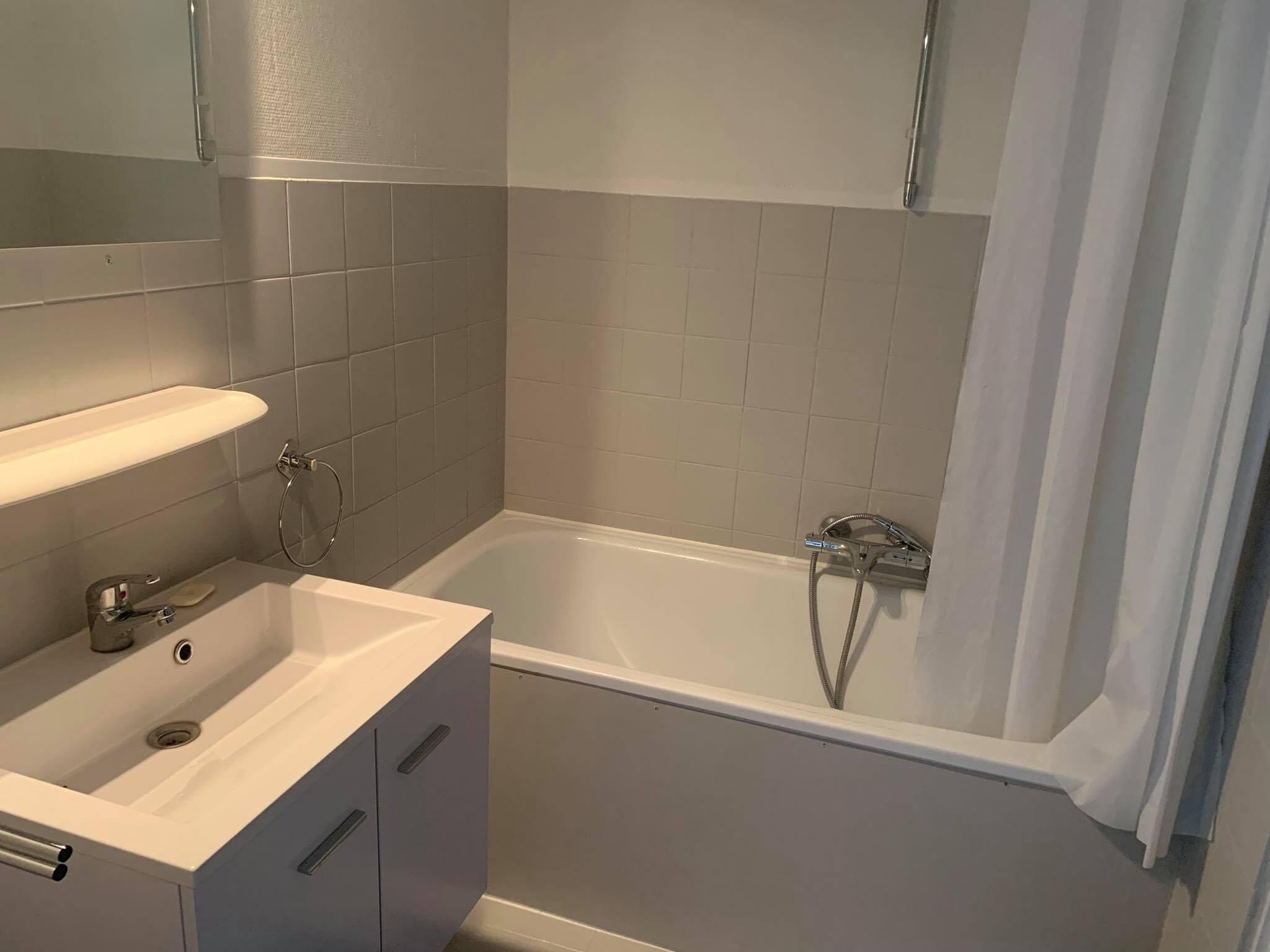A bathroom with a white sink, mirror, and bathtub.