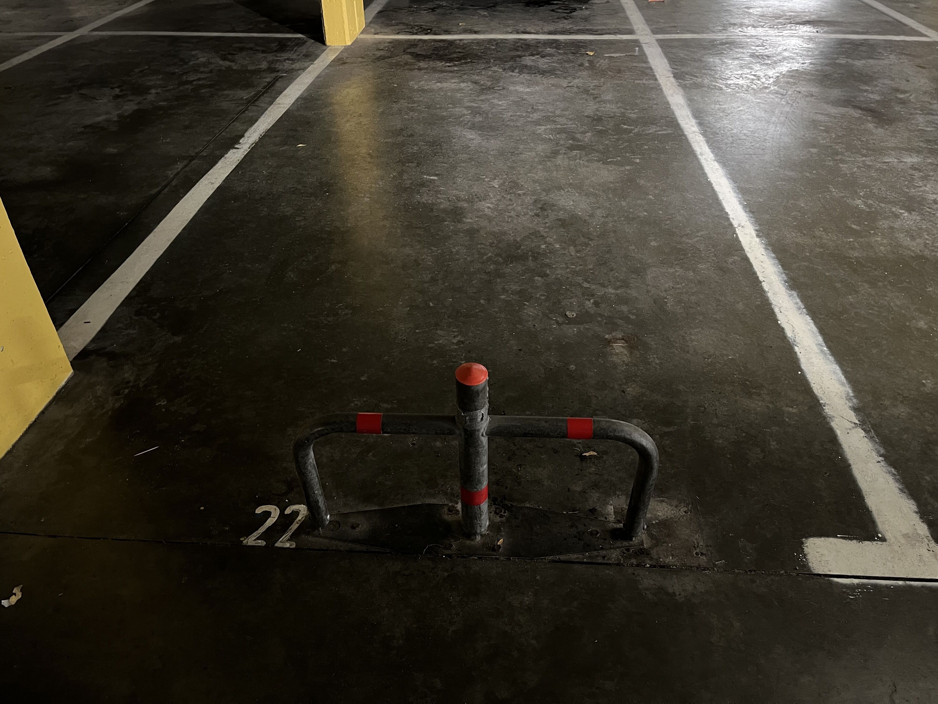 A parking space with a metal barrier and a number "22" on the floor.