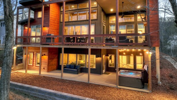 Une cabane moderne à plusieurs étages, dotée d’un balcon, de grandes fenêtres et d’un bain à remous.