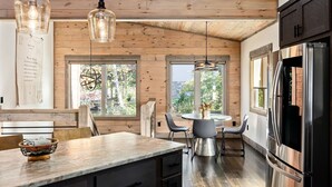 Une cuisine moderne avec des murs en bois, un grand îlot central et un réfrigérateur en acier inoxydable.