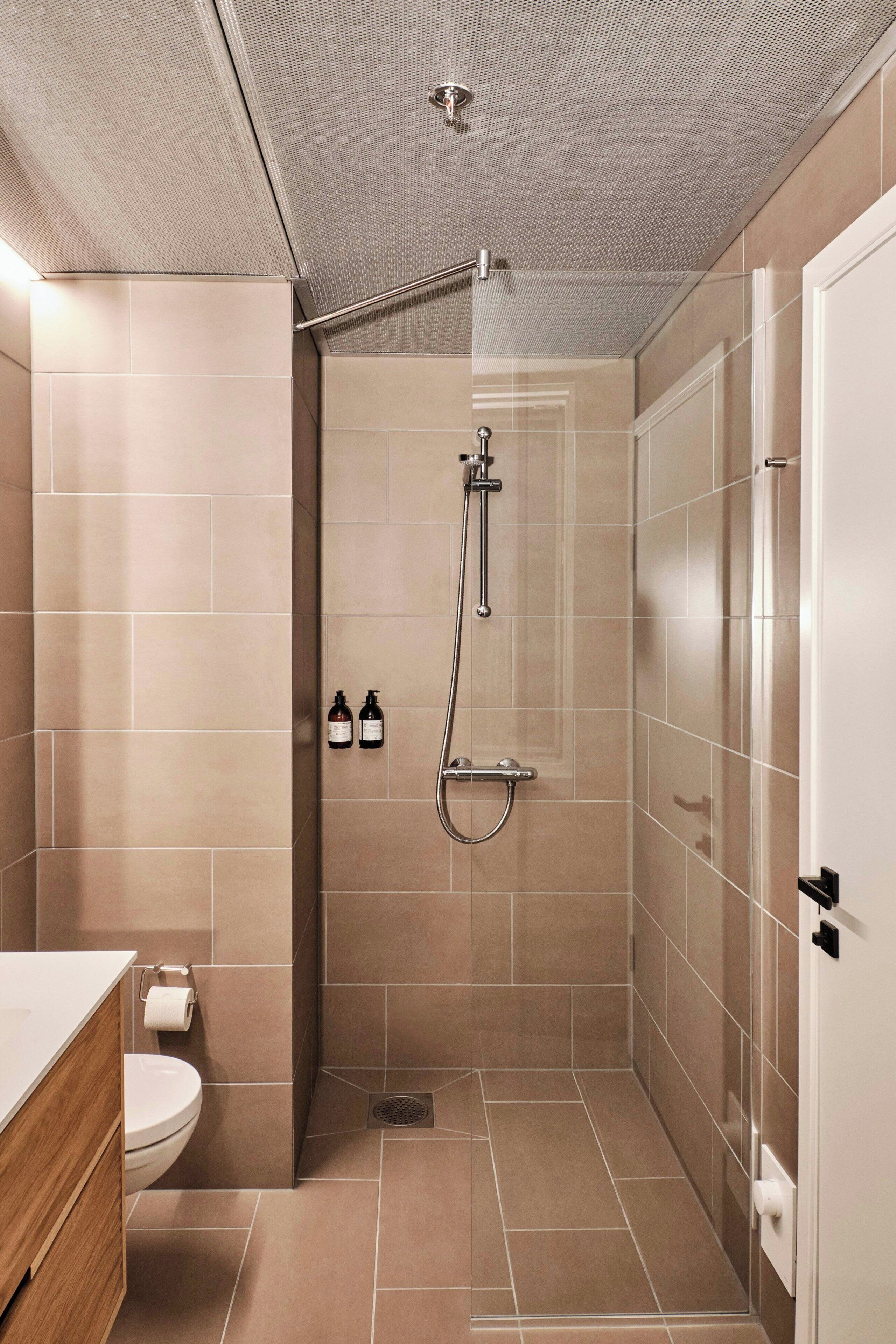 Een moderne badkamer met douche, toilet en wastafel.
