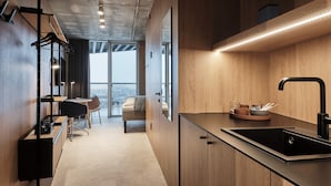 A modern kitchen with a black sink, wooden cabinets, and a dining area with a chair and table.