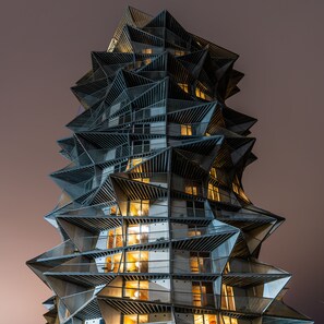 Ein modernes, mehrgeschossiges Gebäude mit einem markanten, winkligen Design, inklusive Balkone und Fenster.