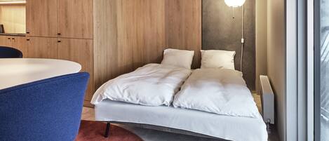 Un dormitorio moderno con cama, escritorio y ventana grande.