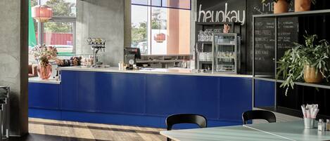 A modern restaurant interior with a blue counter, black chairs, and a menu board.
