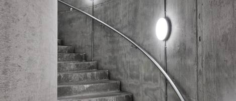 A concrete staircase with metal handrails and circular wall-mounted lights.