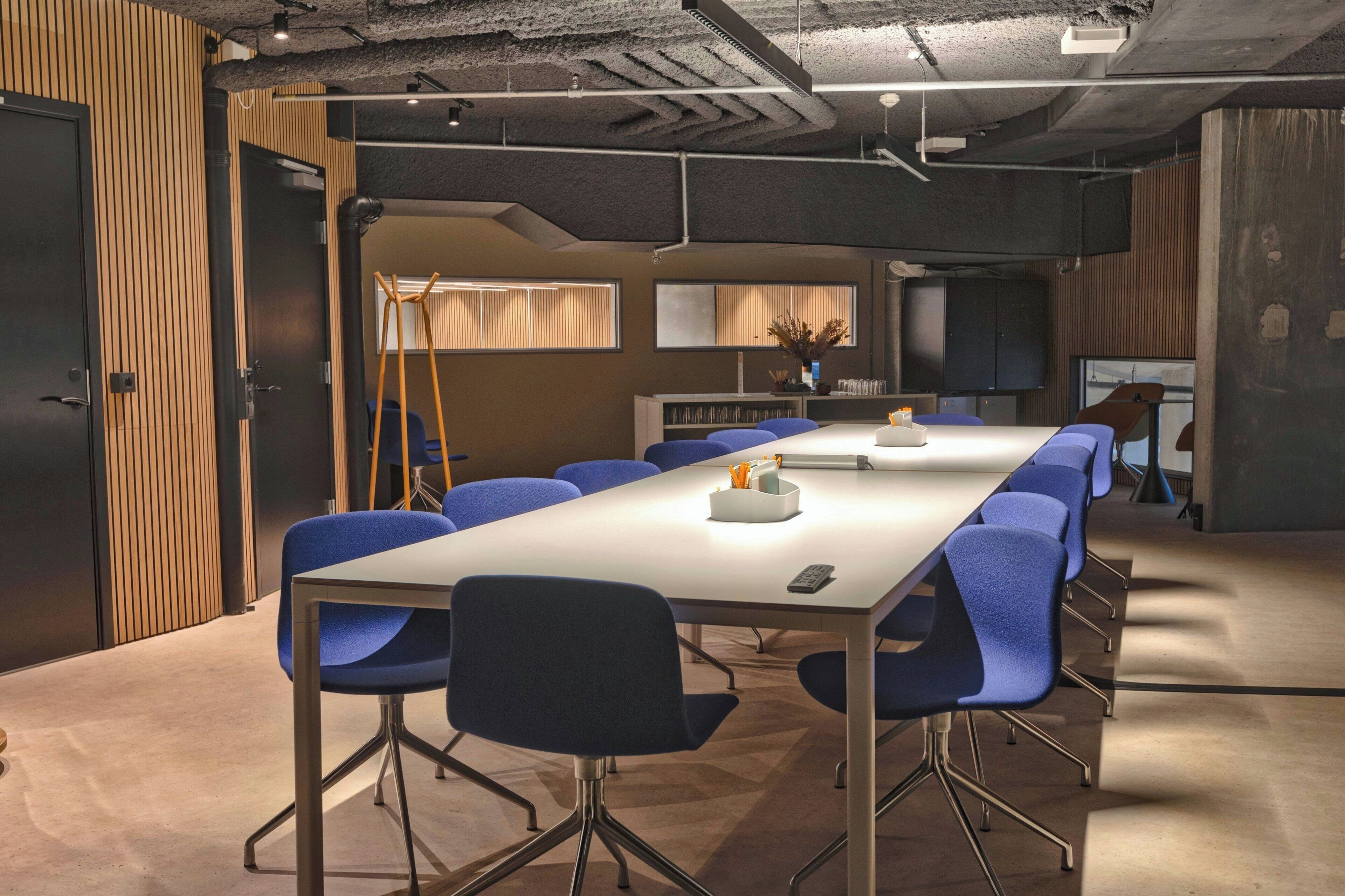 Une salle de conférence dotée d’une longue table, de chaises bleues et d’un design moderne.