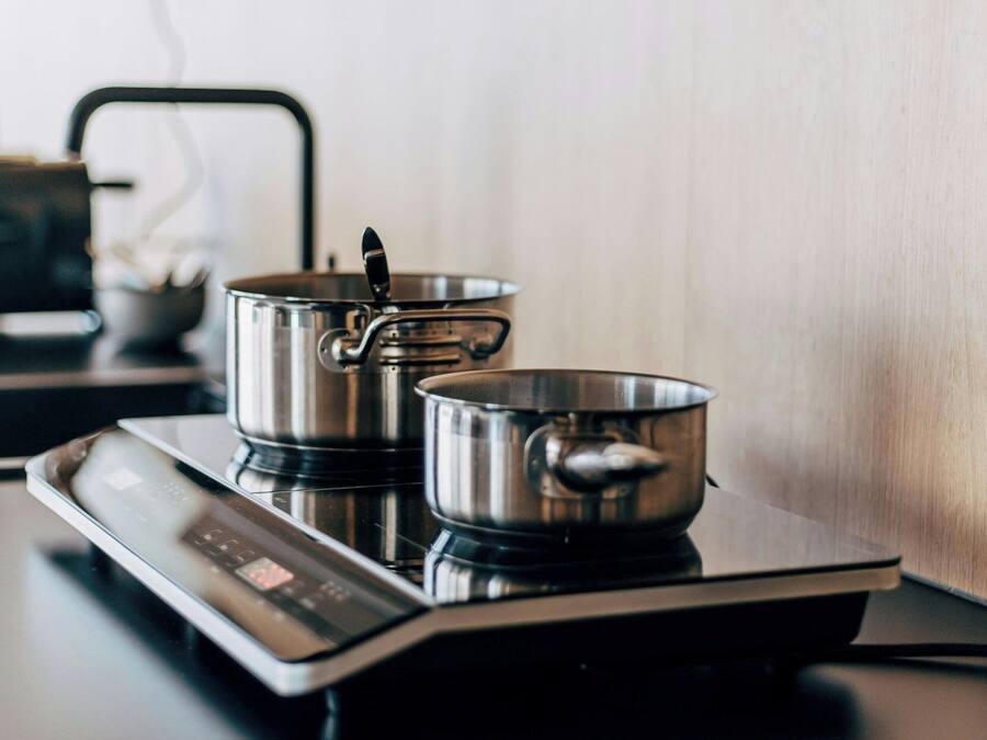 A kitchen with an induction cooktop, two pots, and a cutting board with apple slices.
