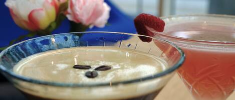Deux boissons sur une table, avec une chaise bleue et une fleur en arrière-plan.