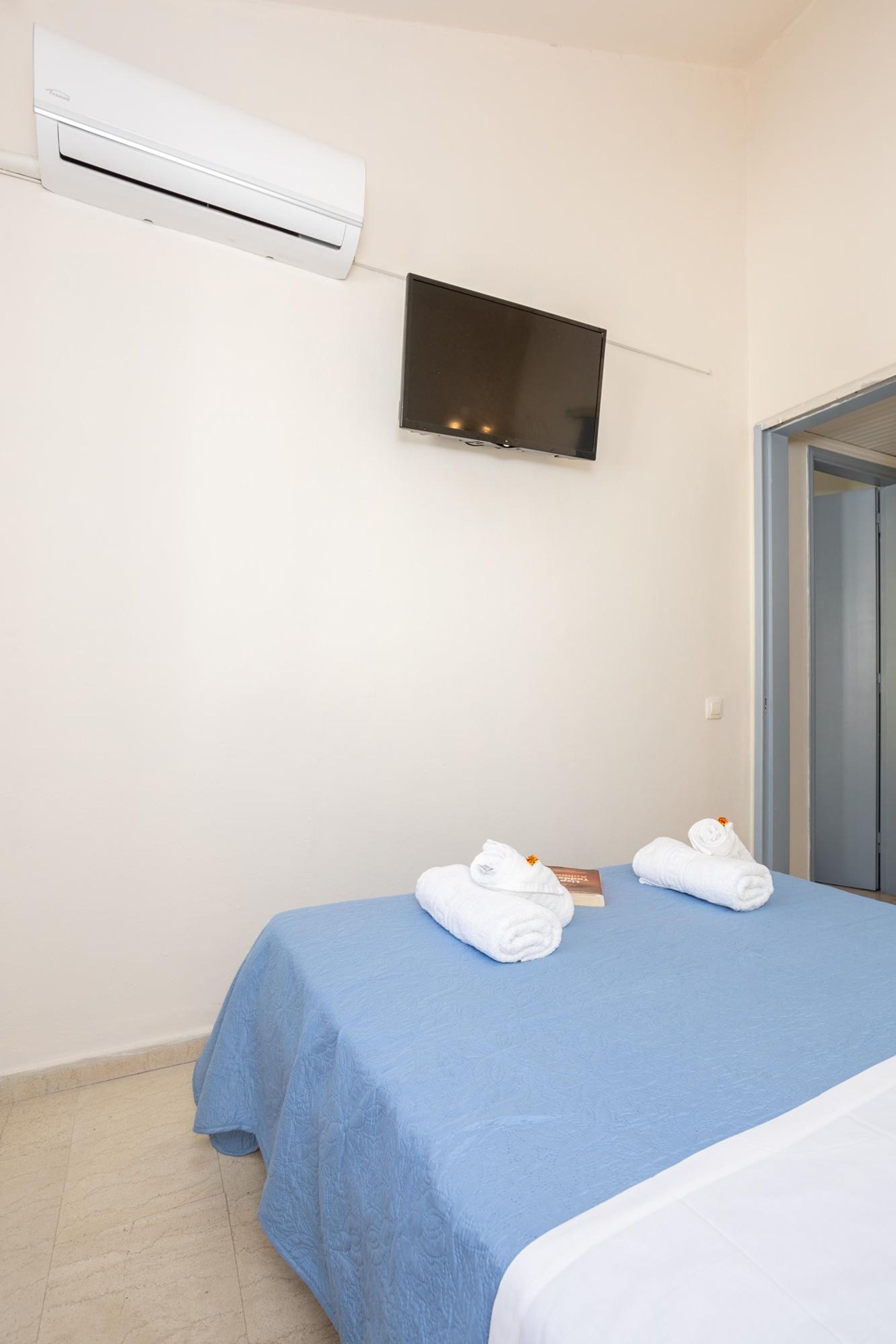 Camera da letto con un letto, condizionatore, televisore a schermo piatto e una porta.