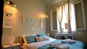 Un lit bien fait, recouvert d’une couvre-lit turquoise et agrémenté d’oreillers, une table de chevet avec une lampe et une fenêtre avec des rideaux.